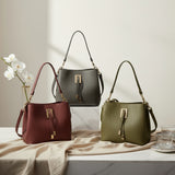 Structured bucket handbag with a gold bar clasp shown in burgundy, grey and olive