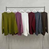 Six drop shoulder knit tops hanging on a rail, side slits visible at the hem