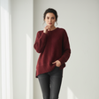 Red textured knit top with a split hem, worn with dark skinny jeans