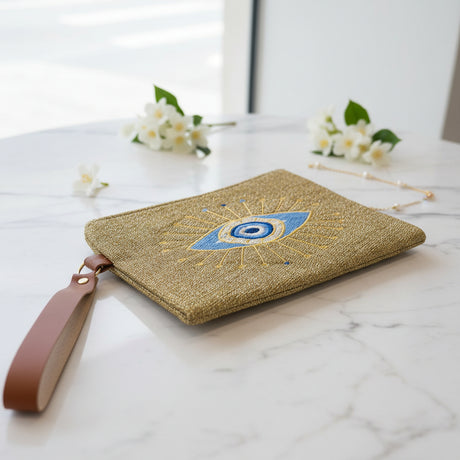 Woven pouch with one large embroidered evil eye inside a gold sunburst of rays