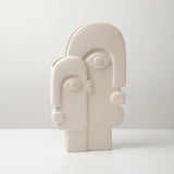 White abstract sculpture of a face on a stand with white background