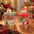 Two clear glass Santa mugs with red and green Santa head lids and striped handles