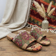 Pair of patterned handmade slippers on a glass shelf with a woven mat in the background