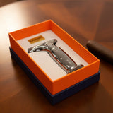 Metallic cigar lighter in an orange and blue box on a wooden surface