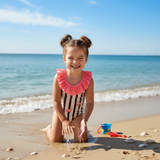 Girl wearing a flamingo print striped onepiece swimsuit at the shoreline