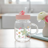 Clear glass mug with a sage green daisy print and a moulded flower lid topper