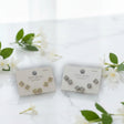 Pair of floral earrings on display cards with a white background and green leaves