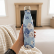 Dusty blue vacuum flask with white cabbage roses held in a knit sleeve