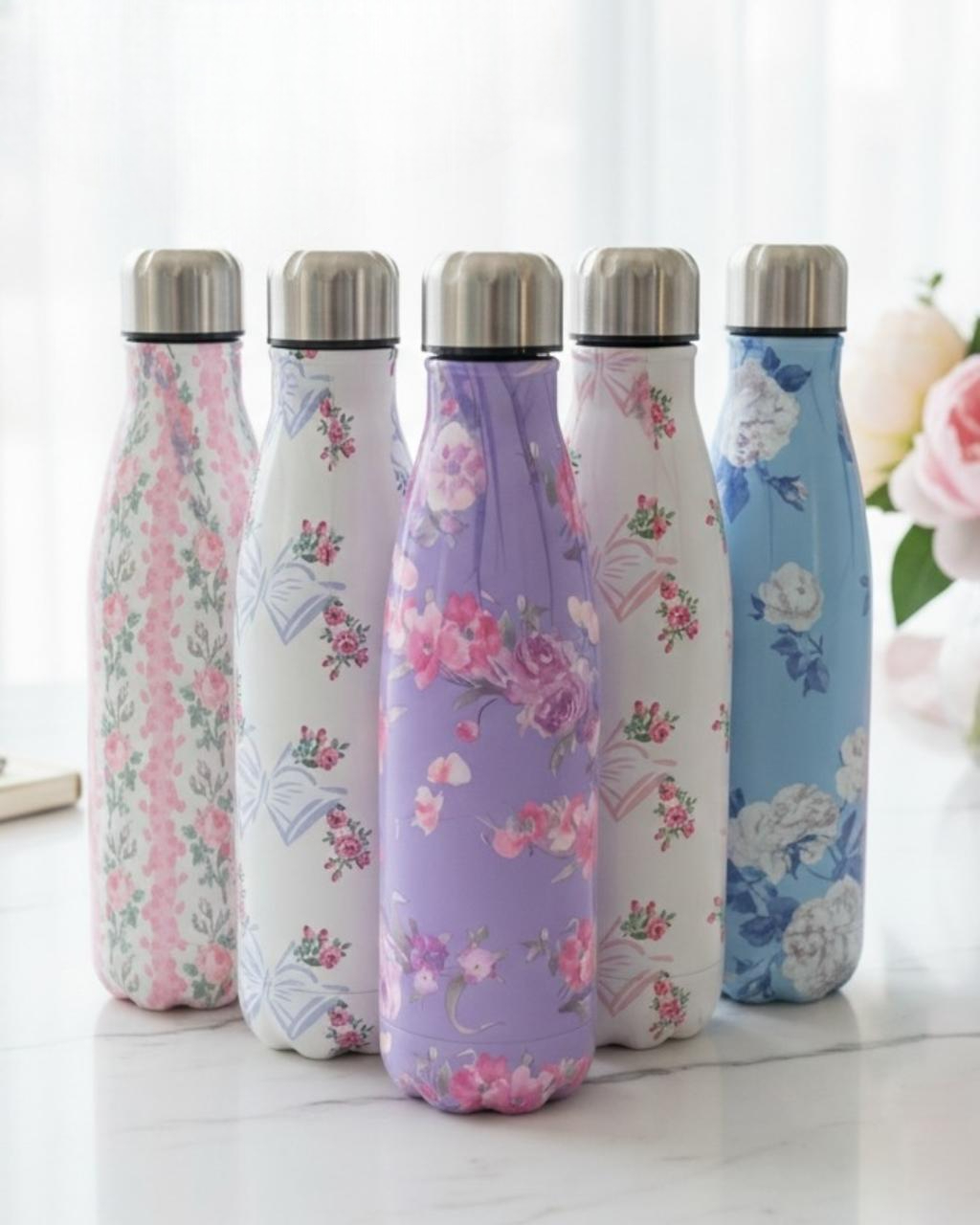 Five vintage rose print vacuum flasks lined up on white marble