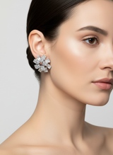 Close-up of a woman wearing a silver flower earring with a grey background