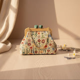 Cream wildflower tapestry bag with a sage green gem clasp against a warm backdrop
