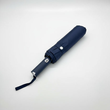 Folded navy blue umbrella on a light grey background