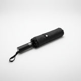 Folded black everyday shield umbrella on a white background