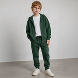 Boy in glasses wearing a forest green zip hoodie and drawstring joggers