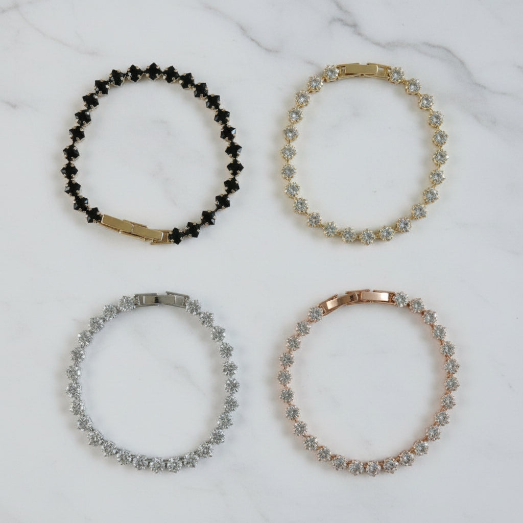Four crystal tennis bracelets on a marble surface
