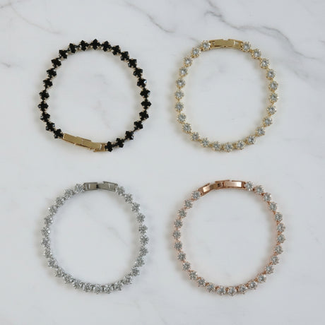 Four crystal tennis bracelets on a marble surface
