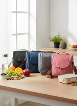 Four colorful lunch bags on a wooden table with fruits and snacks