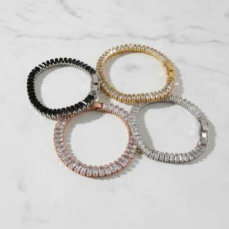 Four premium baguette tennis bracelets on a marble surface
