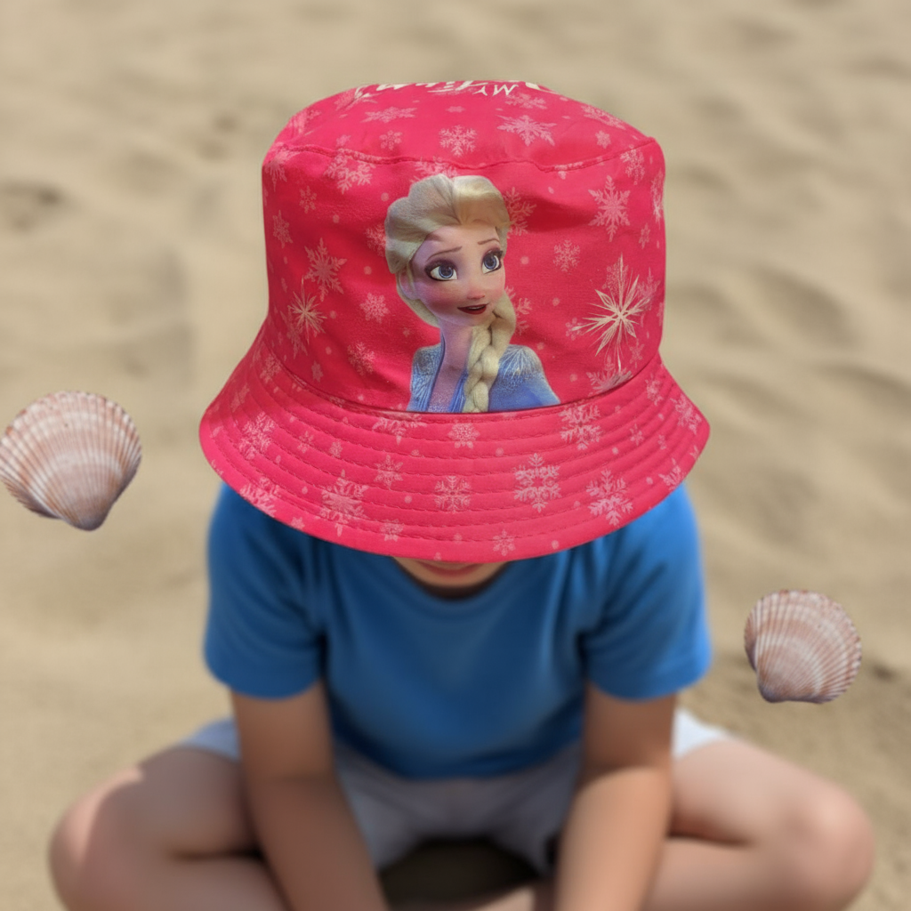 Child seated on sand wearing a bright cerise snowflake bucket hat featuring Elsa