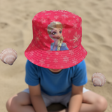 Child seated on sand wearing a bright cerise snowflake bucket hat featuring Elsa