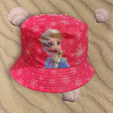 Bright cerise snowflake print bucket hat showing Elsa on the front panel, placed on sand