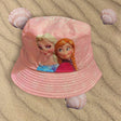 Pale pink bucket hat with Elsa and Anna artwork lying on rippled sand with seashells