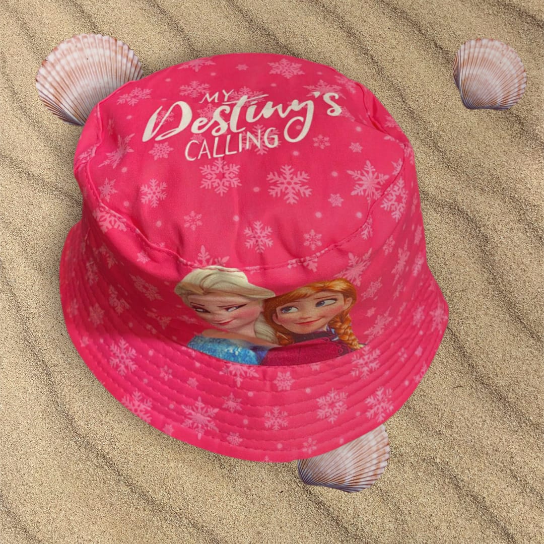 Overhead view of a pink snowflake bucket hat with a script slogan and both sisters below