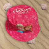 Overhead view of a pink snowflake bucket hat with a script slogan and both sisters below