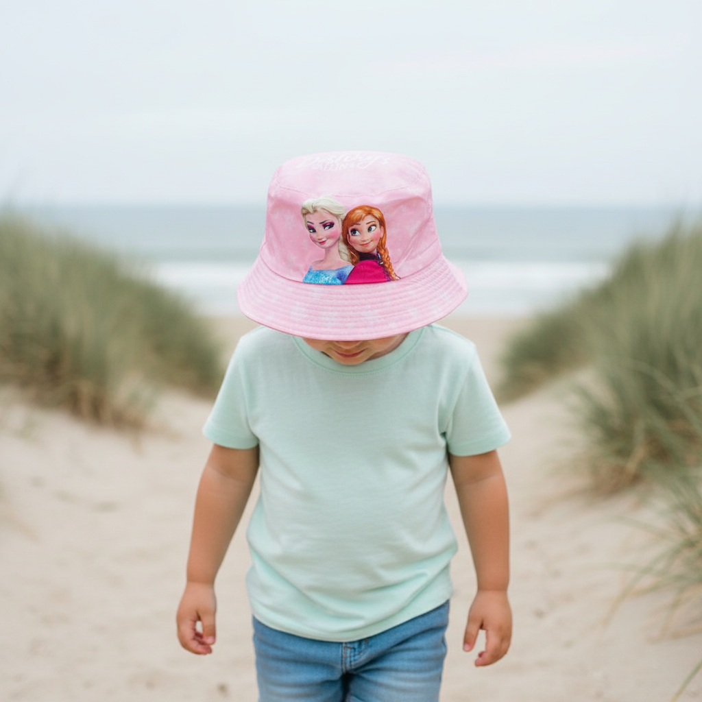 Girl at the beach wearing a pale pink bucket hat printed with Elsa and Anna