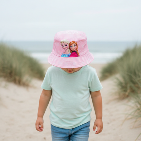 Girl at the beach wearing a pale pink bucket hat printed with Elsa and Anna