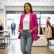 Woman in a fuchsia blazer and blue jeans standing in a clothing store