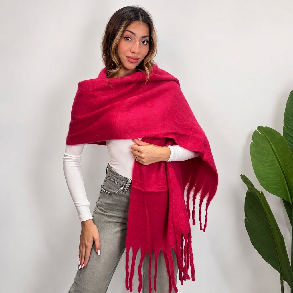 Woman wrapping a fuchsia brushed blanket scarf over one shoulder with long twisted tassels