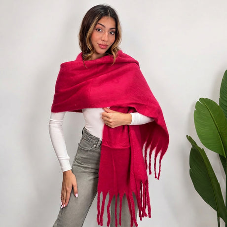 Woman wrapping a fuchsia brushed blanket scarf over one shoulder with long twisted tassels