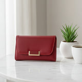 Red wallet with gold clasp on a marble surface with a plant and cup in the background