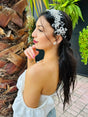 Woman with garden glow tiara and white top standing outdoors with plants in the background