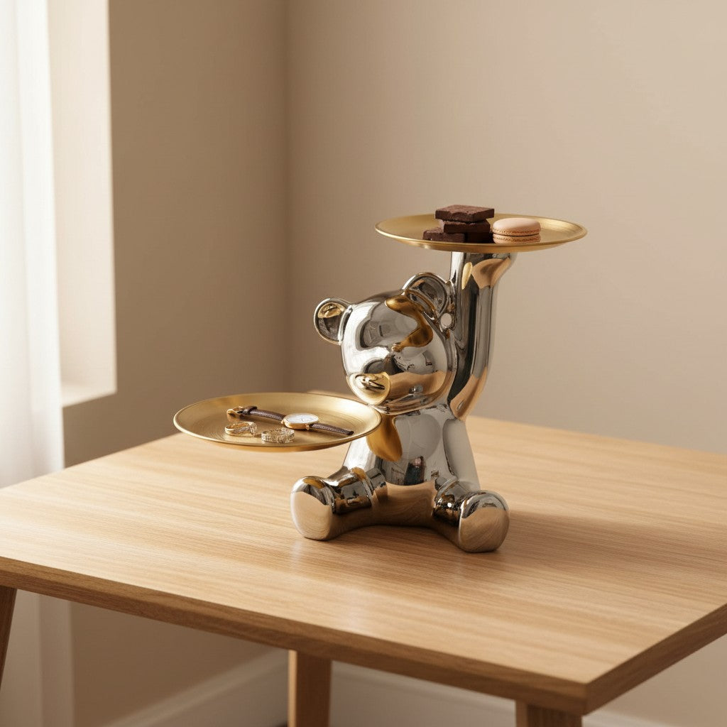 Chrome bear by a window with chocolate squares and a pink macaron in its raised gold tray