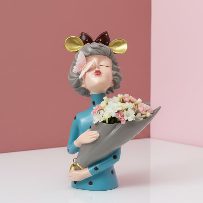 Teal polka dot dress, gold mouse ears and a butterfly on her nose above a grey cone vase