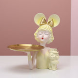 Pale yellow bob, gold bow mouse ears, a gold tray and a small cat holding a Love block