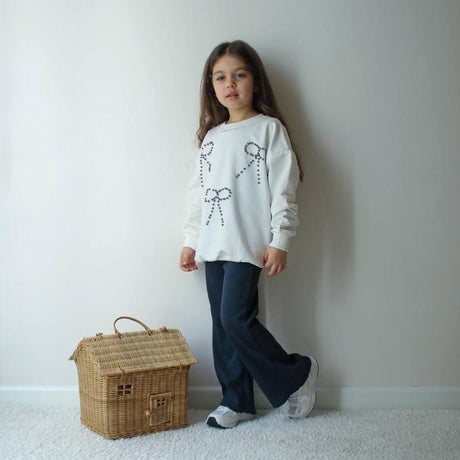 Cream sweatshirt with three beaded bows and navy flared pants