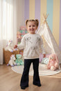 Girl in a cream rhinestone bow sweatshirt and navy flared pants