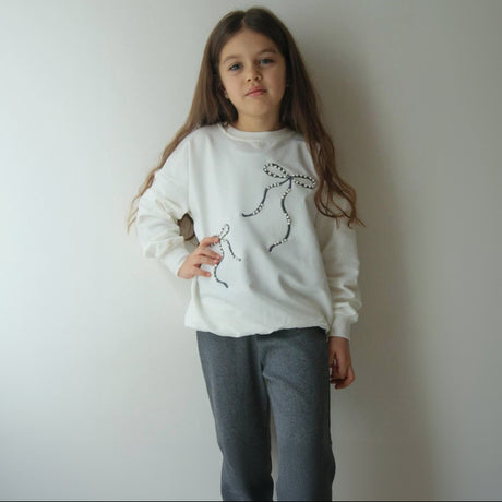 Cream sweatshirt with two beaded bow motifs and dark flared pants
