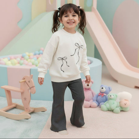 Girl in a cream bow print sweatshirt and charcoal flared pants
