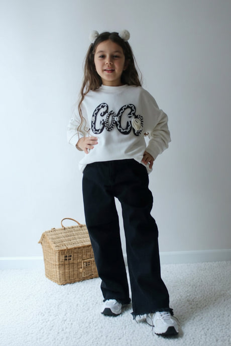 Full length view of an off white slogan sweatshirt with black wide leg frayed hem trousers