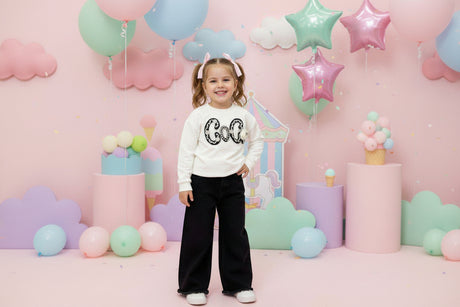 Girls set with a cream textured letter sweatshirt and black wide leg trousers at a party