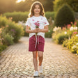 Young girl holding flowers in a garden pathway
