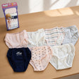 Seven girls cotton briefs in pink, white, stripes, navy and dots laid out beside their pack