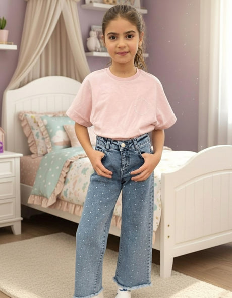 Pearl stud denim jeans worn with a pink tee in a bedroom