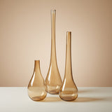 All three amber teardrop vases standing empty side by side in graduated heights