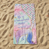 Pastel pink and mint beach towel with a gold outlined mermaid tail on sand