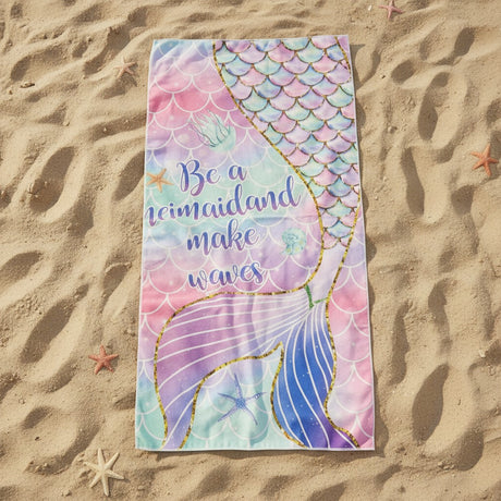 Pastel pink and mint beach towel with a gold outlined mermaid tail on sand